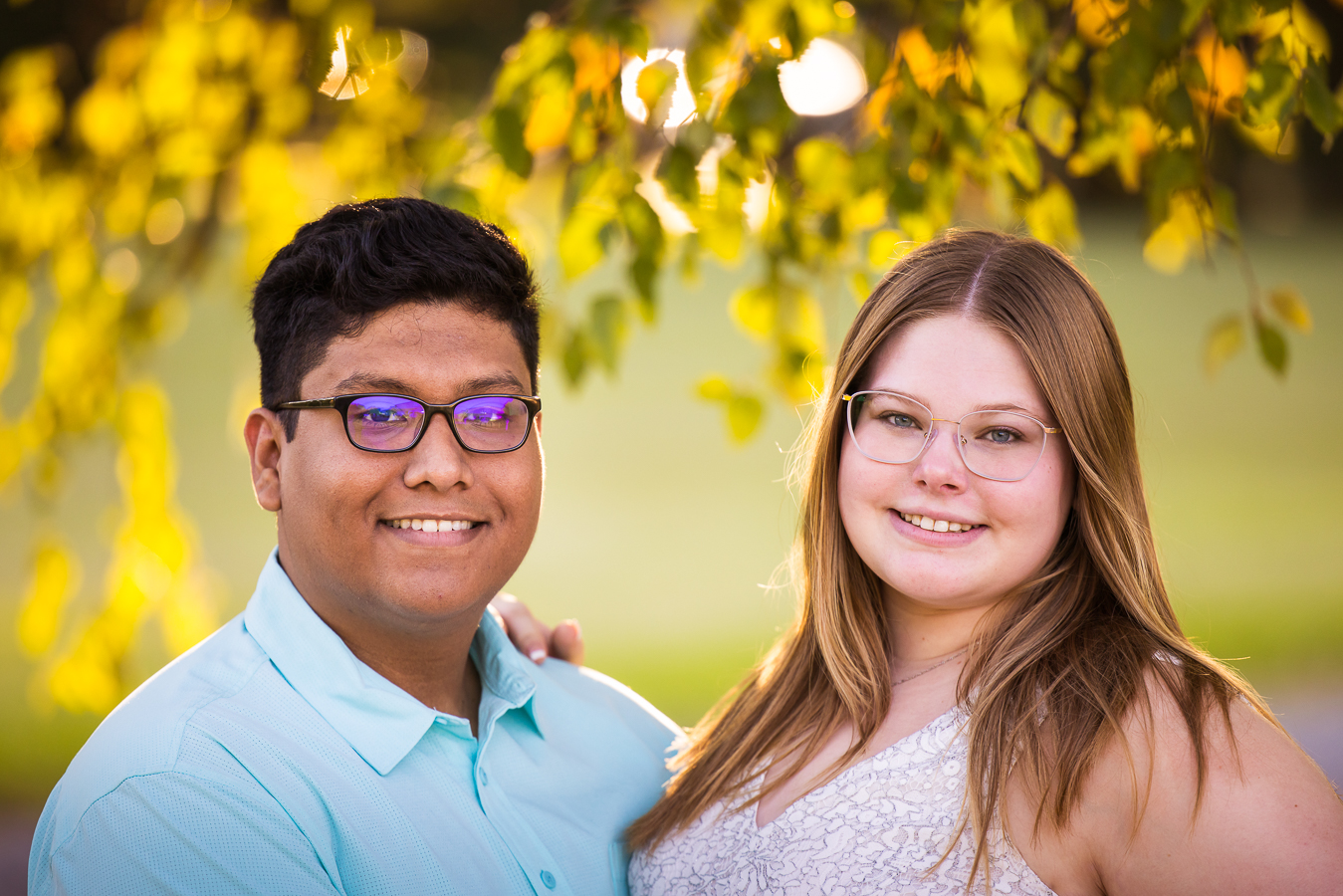 traditional portrait of the couple as they stand side by side smiling at the camera with vibrant, colorful leaves behind them during their cedar ridge community church intimate wedding ceremony 