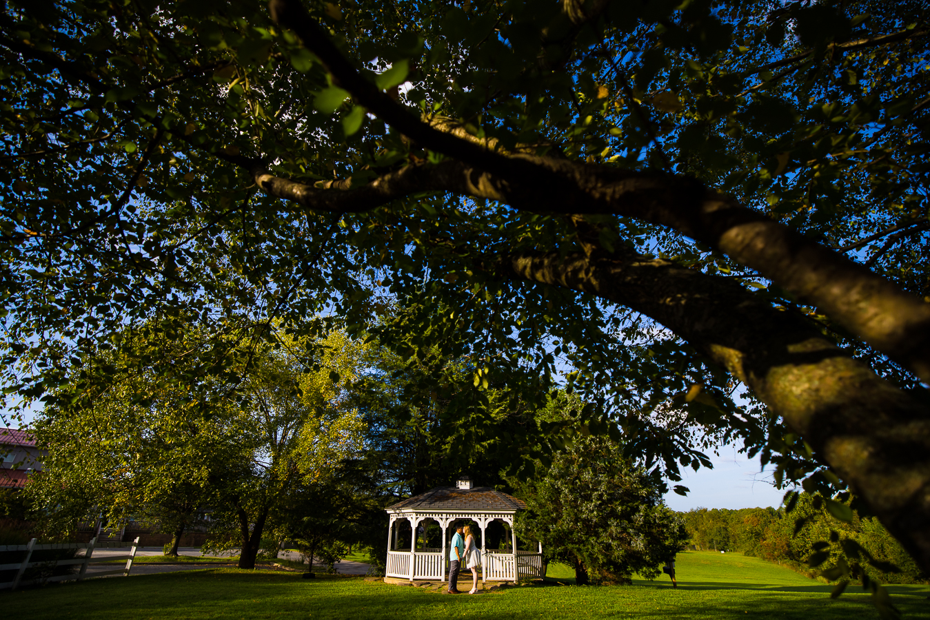 image of the couple as they stand in front of the outdoor gazebo holding hands facing one another as they lean in and kiss during their outdoor intimate wedding ceremony at the cedar ridge community church in spencerville maryland