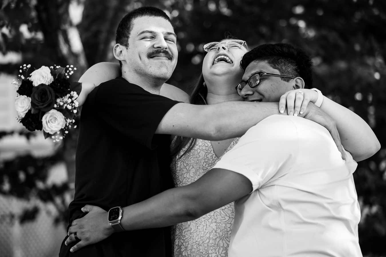 DMV wedding photographer, rhinehart photography, captures this black and white image of the couple with their best man as they all hug one another and laugh during this intimate wedding ceremony in spencerville Maryland 
