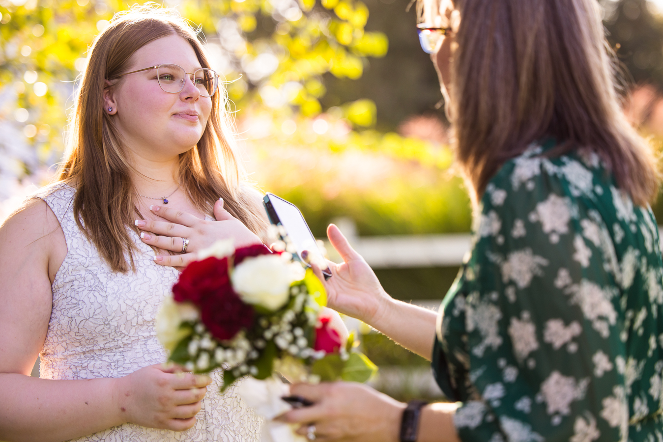 image of the bride as puts her hand over her chest while holding flowers and she looking at her mother during the intimate wedding ceremony in Maryland 