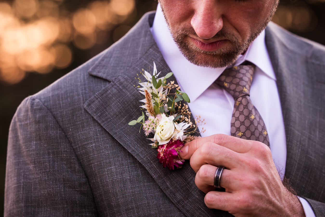 close up image of the groom showing off his vibrant, colorful floral boutonniere made by iron willow floral designs at this wedding venue in warfordsburg pa called alpine acres