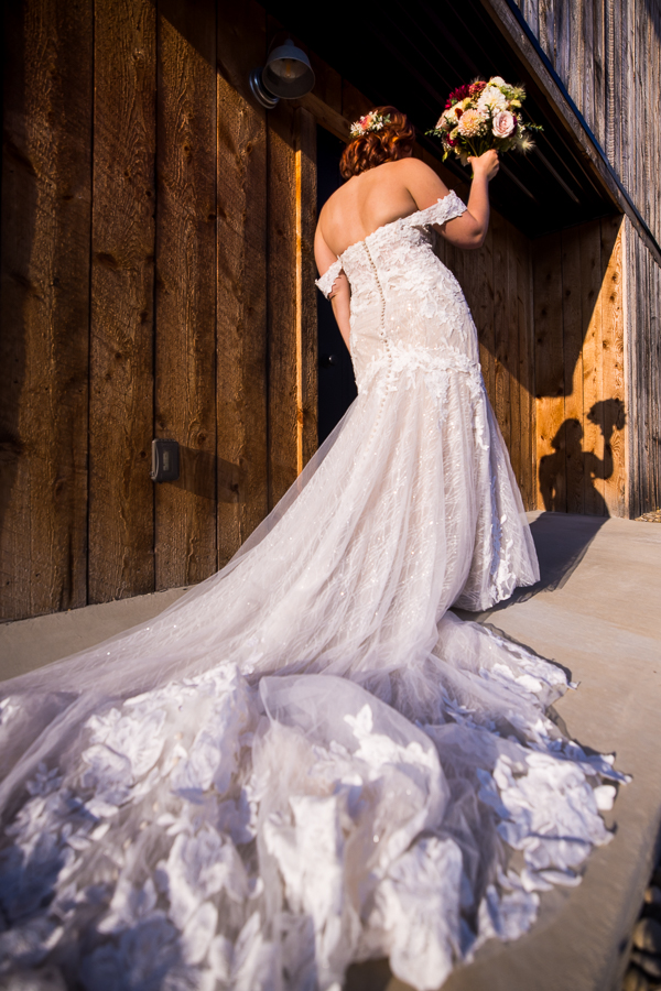 creative wedding photographer, lisa rhinehart, captures this image of the bride showing off her train and dress while her shadow is captured on the rustic barn wood at alpine acres 