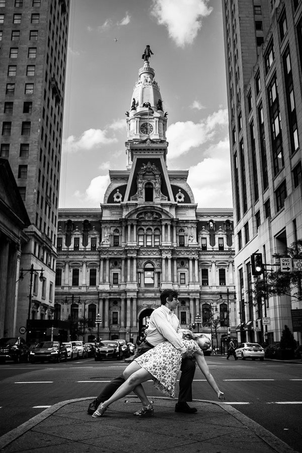 Creative Philadelphia Wedding Photographer, rhinehart photography, captures this black and white image of the couple striking a dance pose in front of city hall in Philly in the middle of the road 