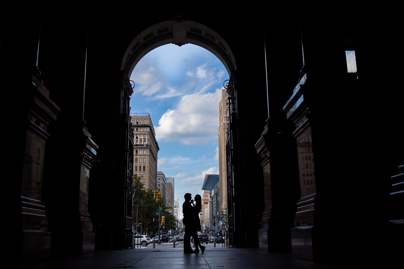 unique, creative image of the couple as they stand under the archway silhouetted while they hold hands and face one another with the vibrant blue sky behind them during their Creative Philadelphia engagement session 