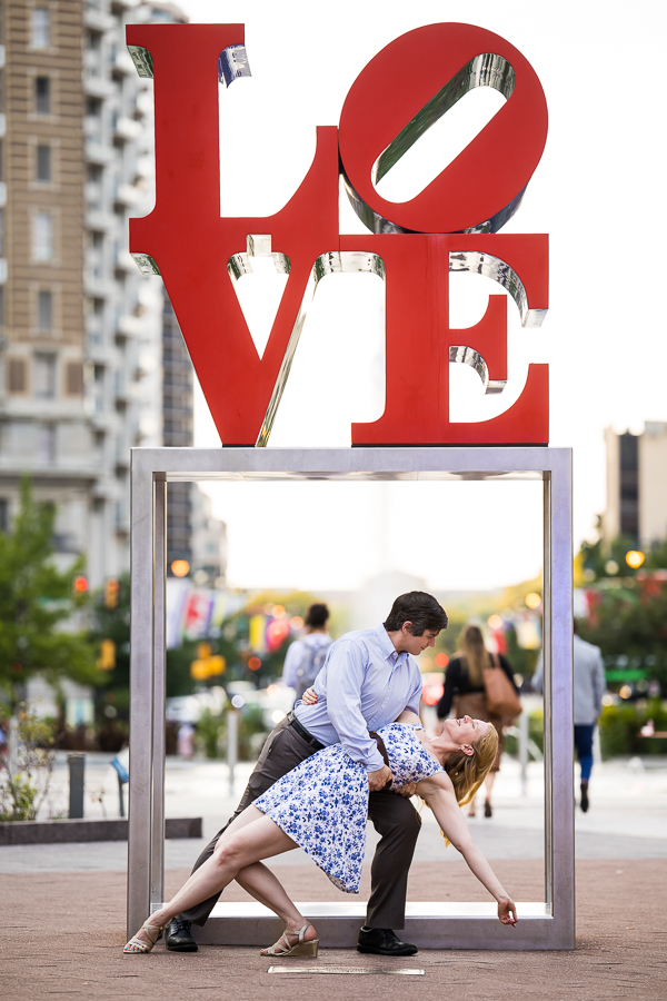 Creative Philadelphia Wedding Photographer, rhinehart photography, captures this unique, fun, creative image of the couple as they dance together underneath the famous love sign in center city Philadelphia during their engagement session 