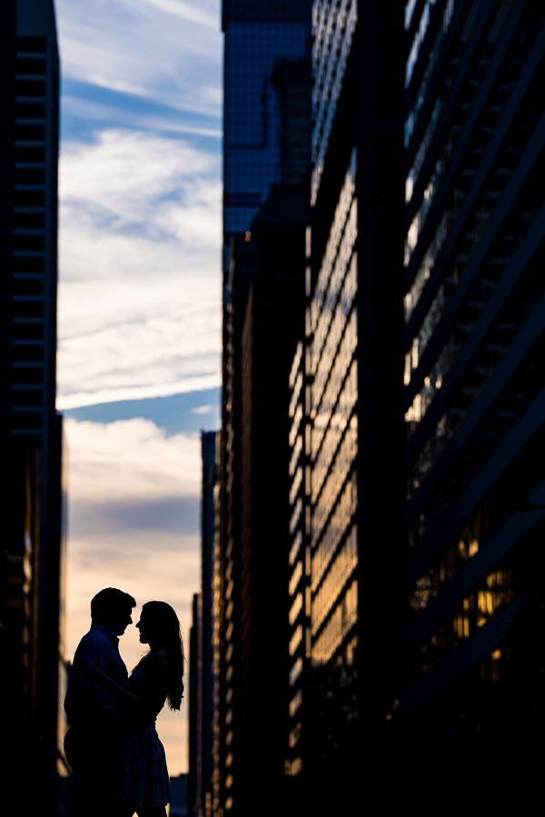 Creative Philadelphia Wedding Photographer, rhinehart photography, captures this creative, vibrant, unique image of the couple as they standing between the buildings silhouetted against the colorful sky as the sun sets during their philly engagement session 