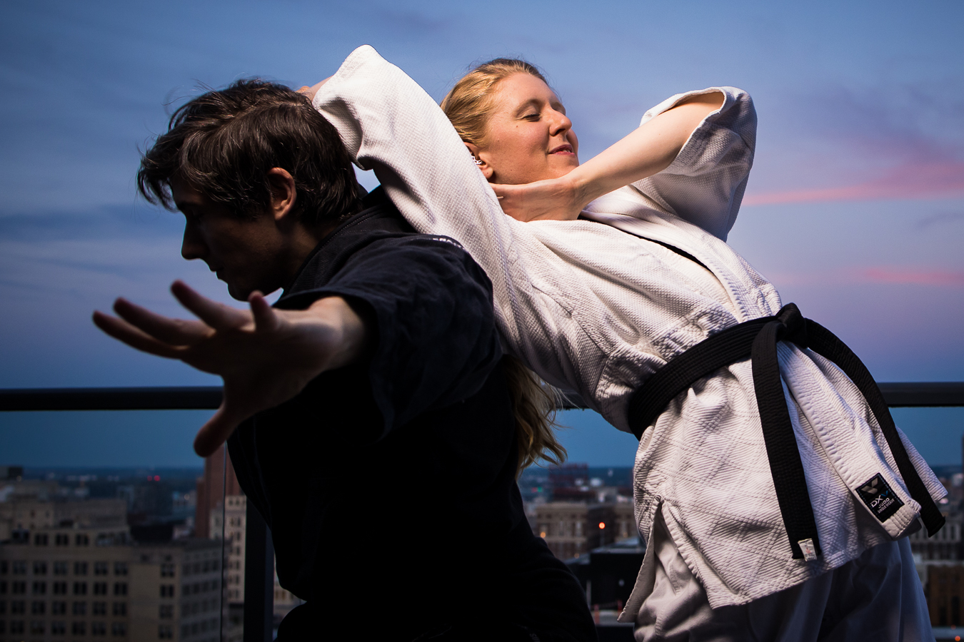 jiu-jitsu engagement photographer, lisa rhinehart, captures this fun, creative image of the couple as they do jiu-jitsu together on the rooftop of their apartment while the sun sets behind them 