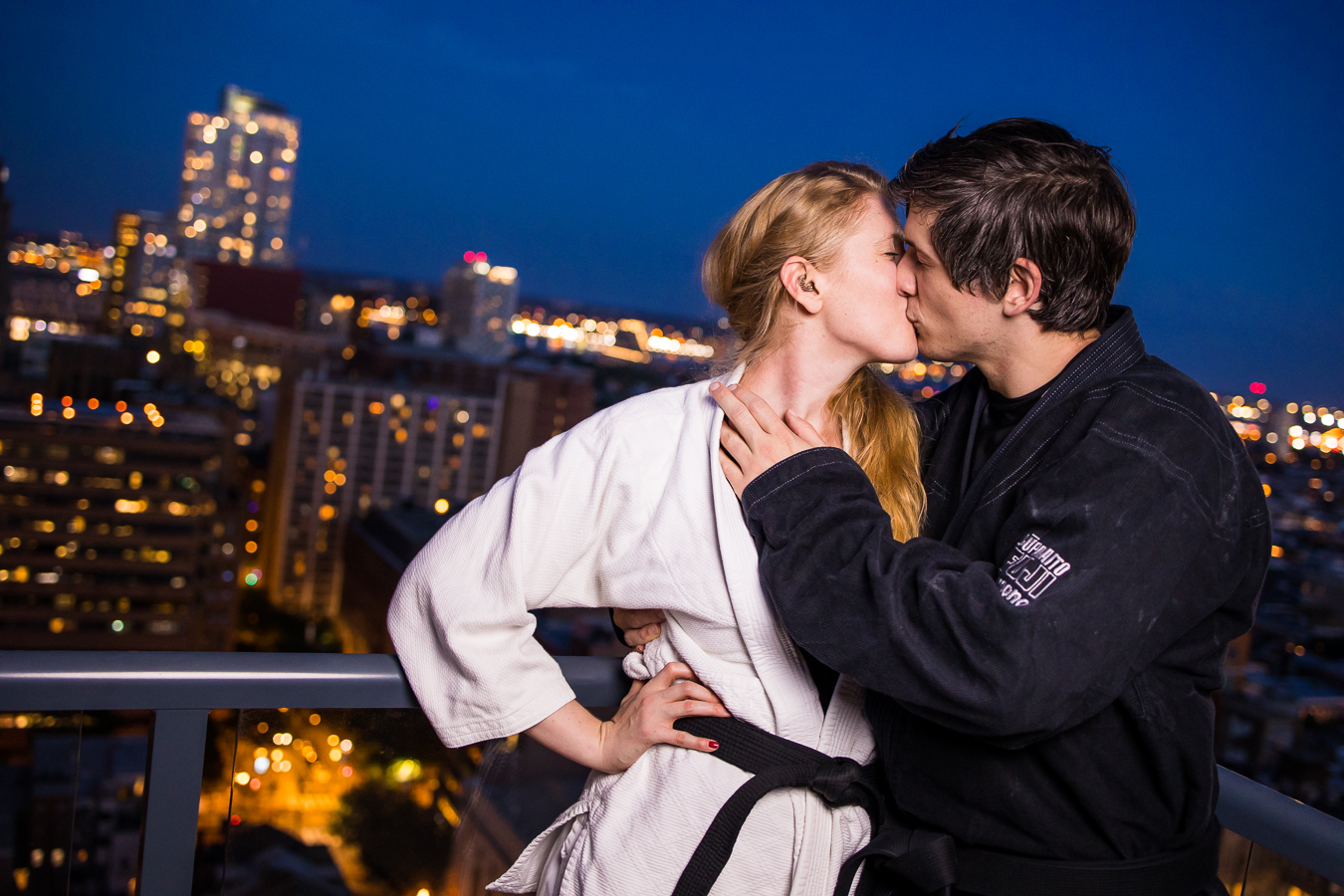 Creative Philadelphia Wedding Photographer, lisa rhinehart, captures this night time shot of the couple as they kiss on the rooftop of their apartment in their jiu-jitsu attire during their creative engagement session in center city Philadelphia 
