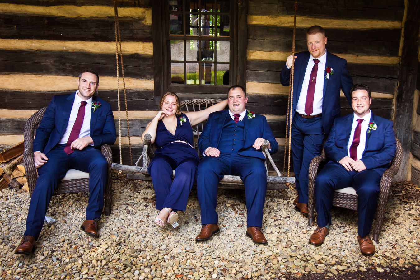 this Pittsburgh wedding photographer captures this unique wedding party featuring the best woman and the rest of the guys sitting on an outdoor swing in their vibrant navy attire