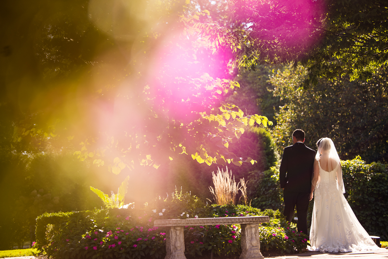 creative wedding photographer, lisa rhinehart, captures this fun, creative colorful image of the bride and groom as they hold hands and walk through the outdoor gardens at the palace at somerset park in new jersey before their black and gold wedding ceremony 