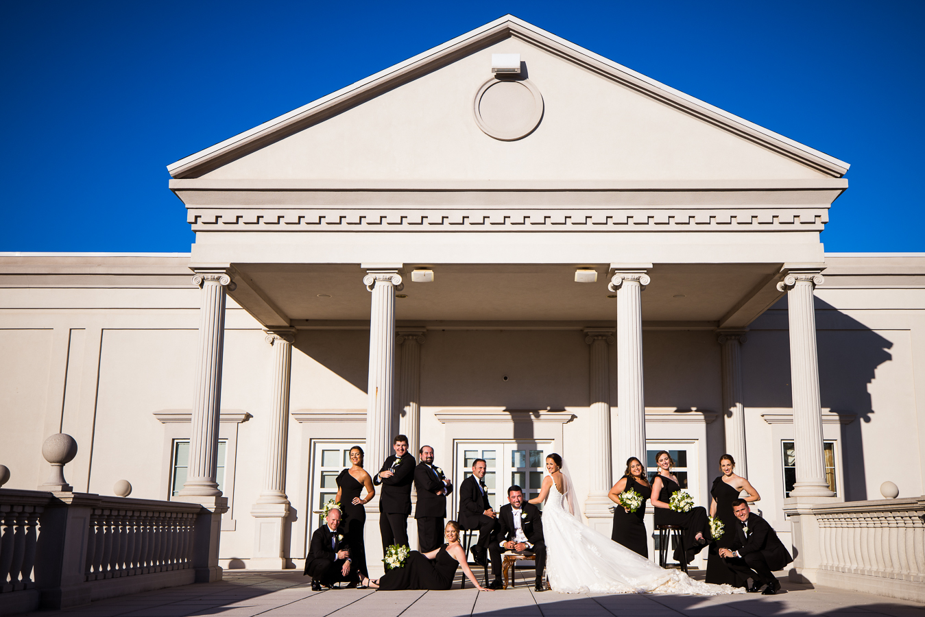 vogue nj wedding photographer, lisa rhinehart, captures this vogue, high end shot of the bride and groom with their black and gold wedding party outside of the palace at somerset park in new jersey 