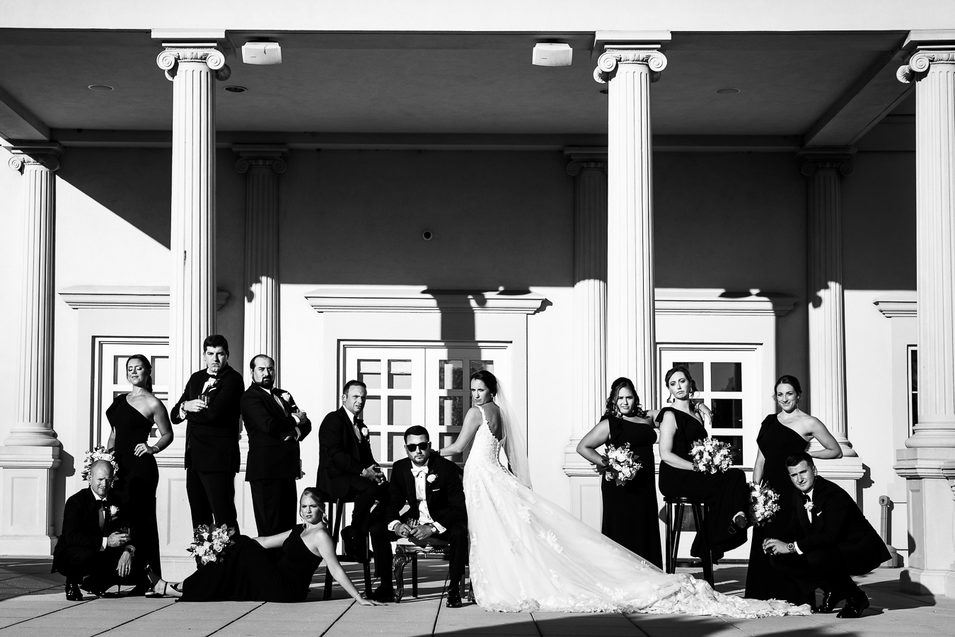 luxury nj wedding photographer, lisa rhinehart, captures this black and white vogue wedding party shot of the bride and groom and their wedding party posing in front of the palace at somerset park during before their black and gold wedding ceremony 