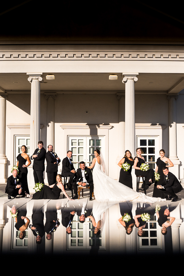 creative nj wedding photographer, lisa rhinehart, captures this creative, reflective image of the bride and groom with their black and gold wedding party in this vogue wedding party shot outside of the palace at somerset park 