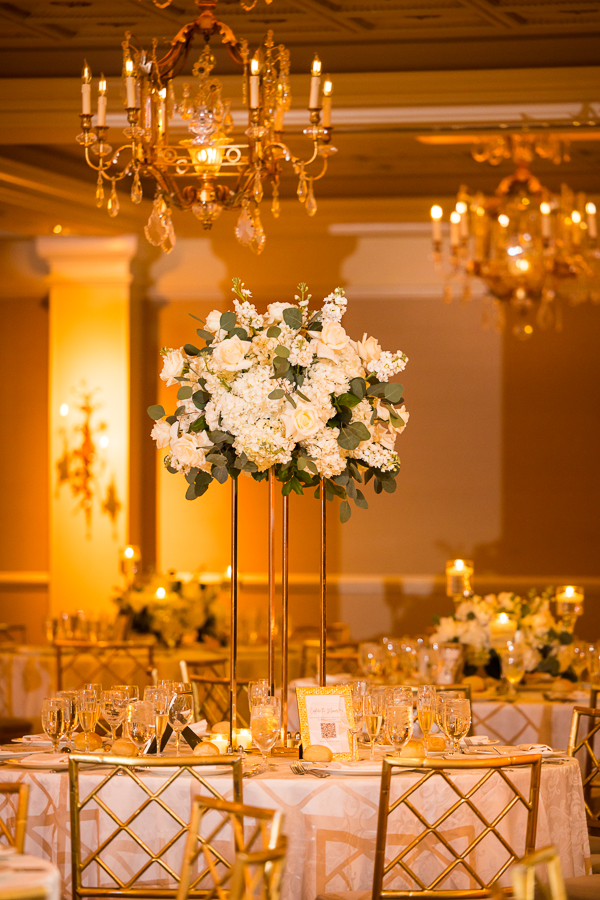 black and gold wedding theme decor inspiration: image of the table decor featuring elevated floral centerpieces, gold chairs, and more