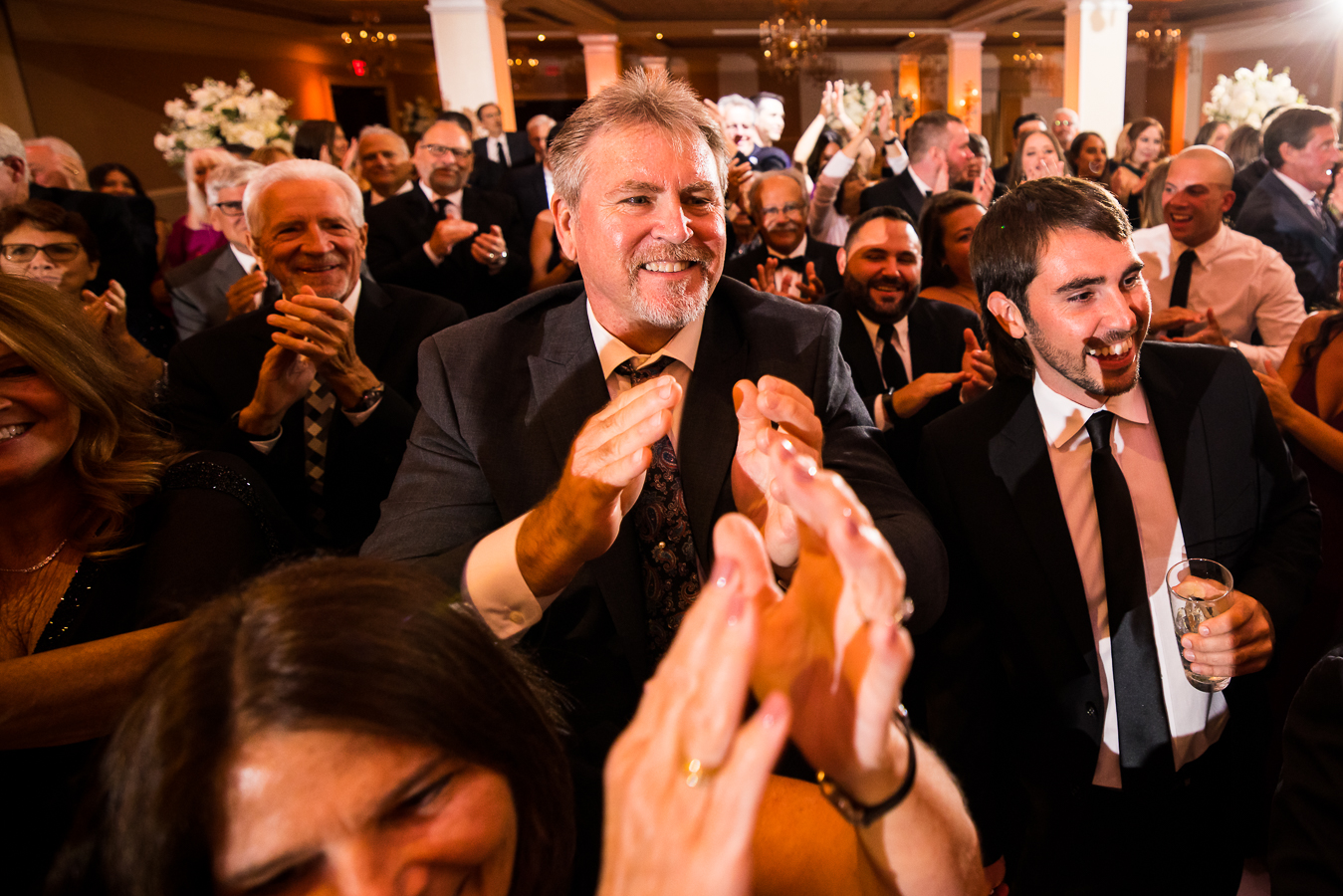 fun image of wedding guests as they clap and cheer while the wedding party, parents and bride and groom enter