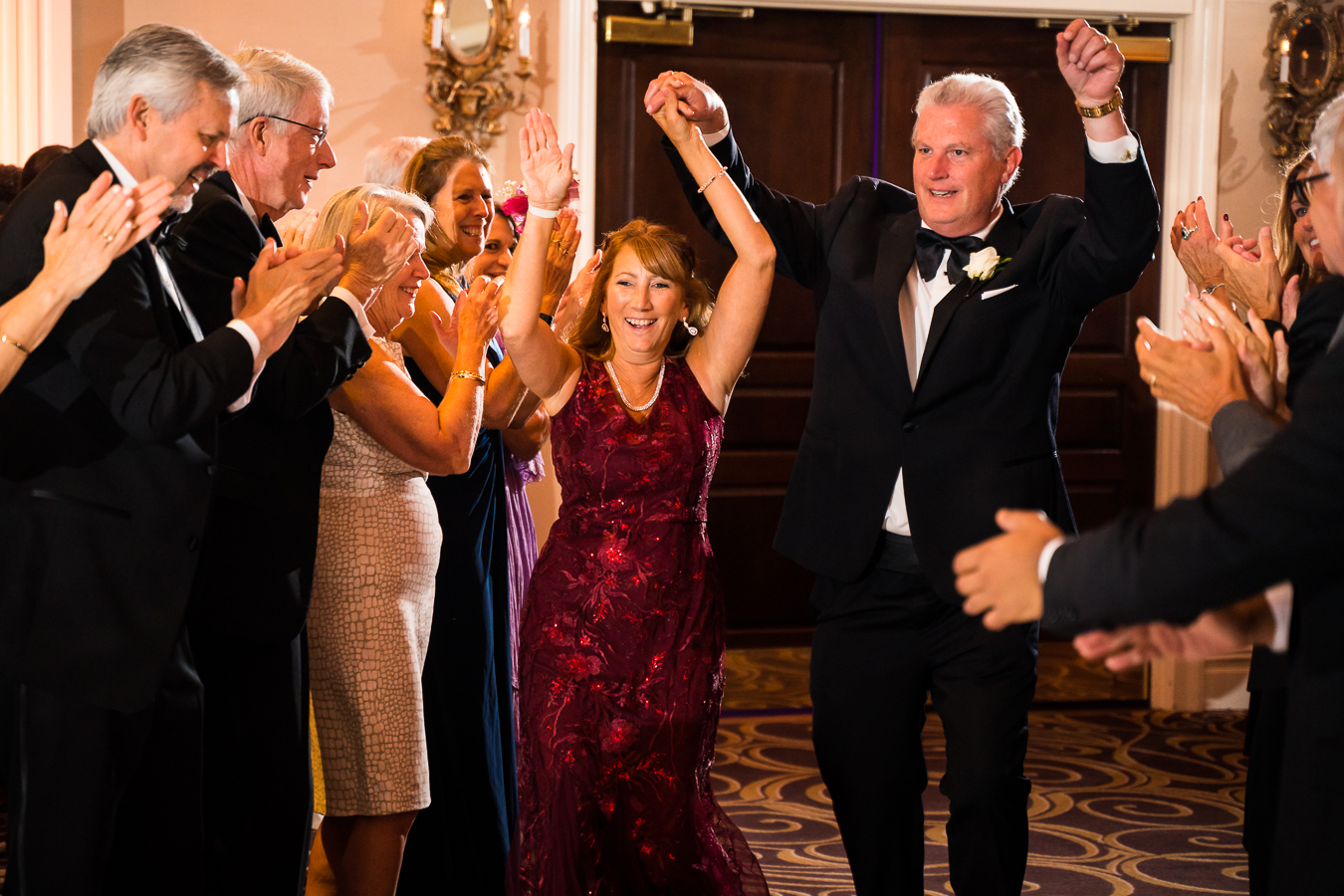 fun image of wedding guests as they clap and cheer while the parents of the groom enter this palace at somerset park wedding reception 
