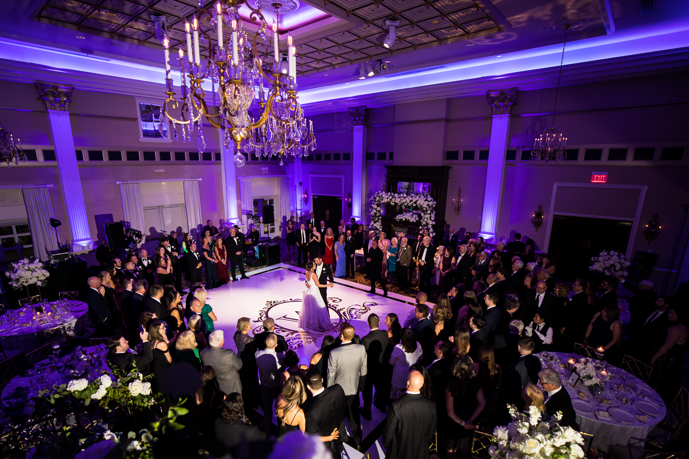 nj wedding photographer, lisa rhinehart, captures this unique, aeriel shot of the bride and groom as they share their first dance together as guests crowd around to watch them during this palace wedding reception in somerset nj