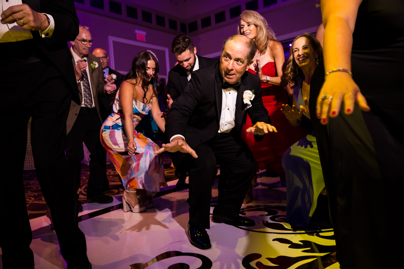 nj wedding photographer, lisa rhinehart, captures wedding guests getting low as they dance on the gold monogramed dance floor during this palace at somerset park wedding reception 