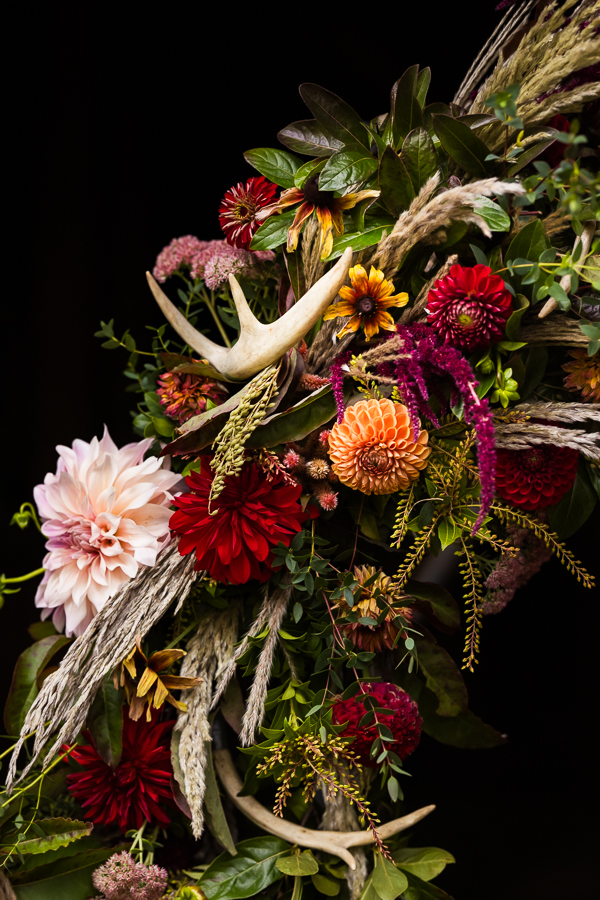 country wedding inspo of the vibrant, colorful fall wedding florals that have antlers intertwined with them for this outdoor country barn wedding