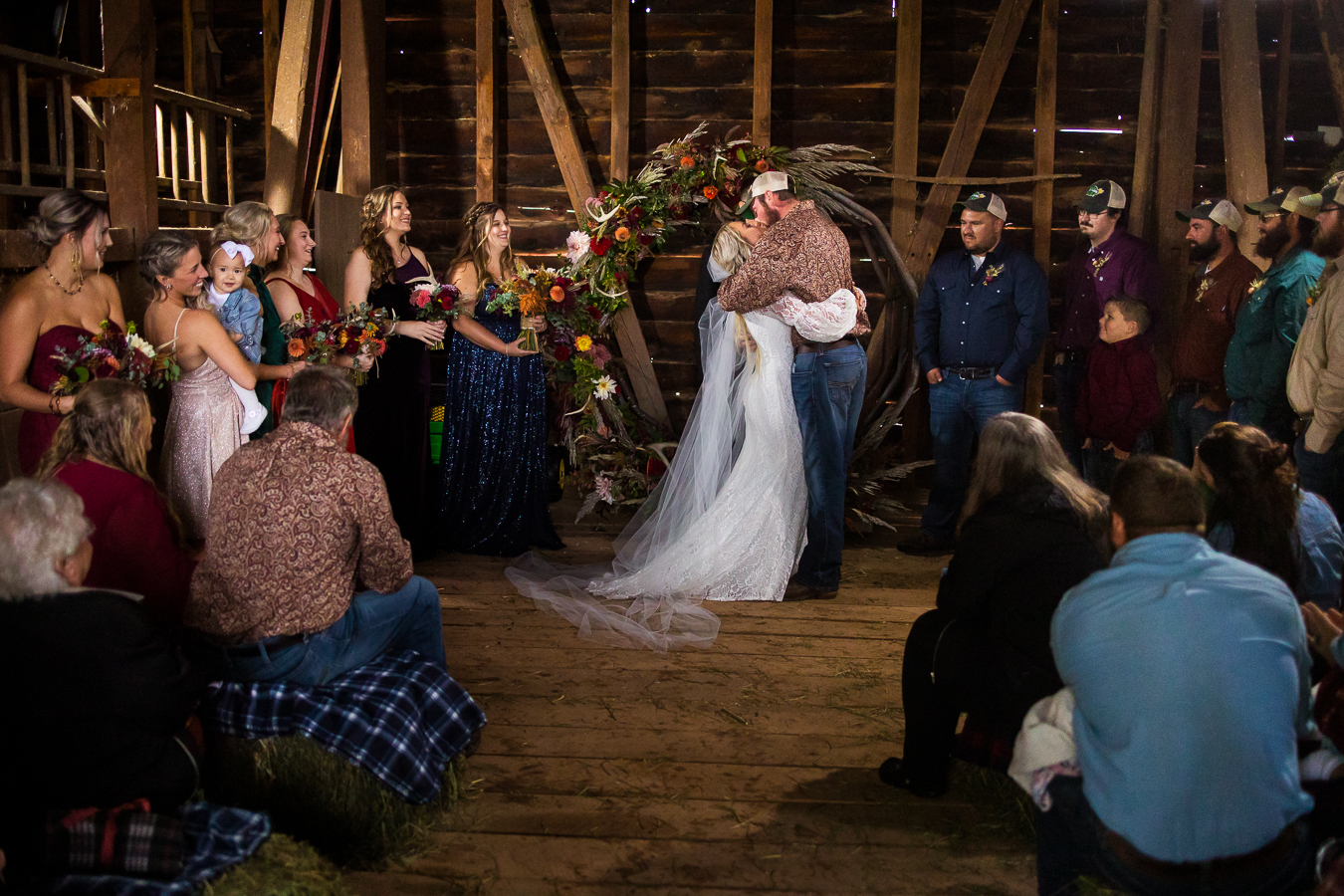 wild country wedding photographer, lisa rhinehart, captures the first kiss between husband and wife as they as surrounded by family and friends during this barn wedding ceremony in halifax pa 