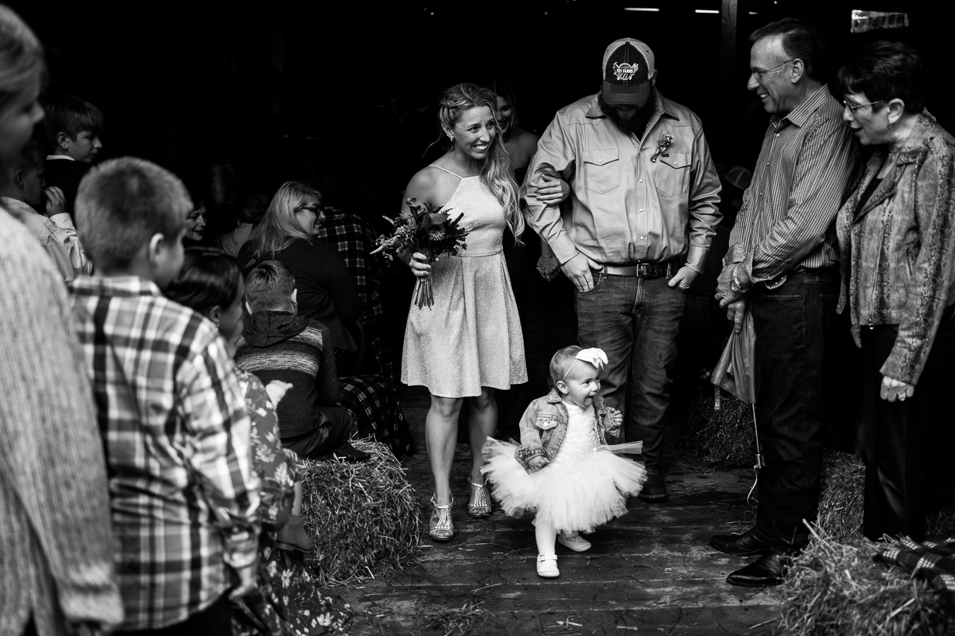 best pa wedding photographer, lisa rhinehart, captures this candid moment as the wedding party exits the barn and the flower girl runs out of the barn in her puffy tutu at the end of this country wedding ceremony 