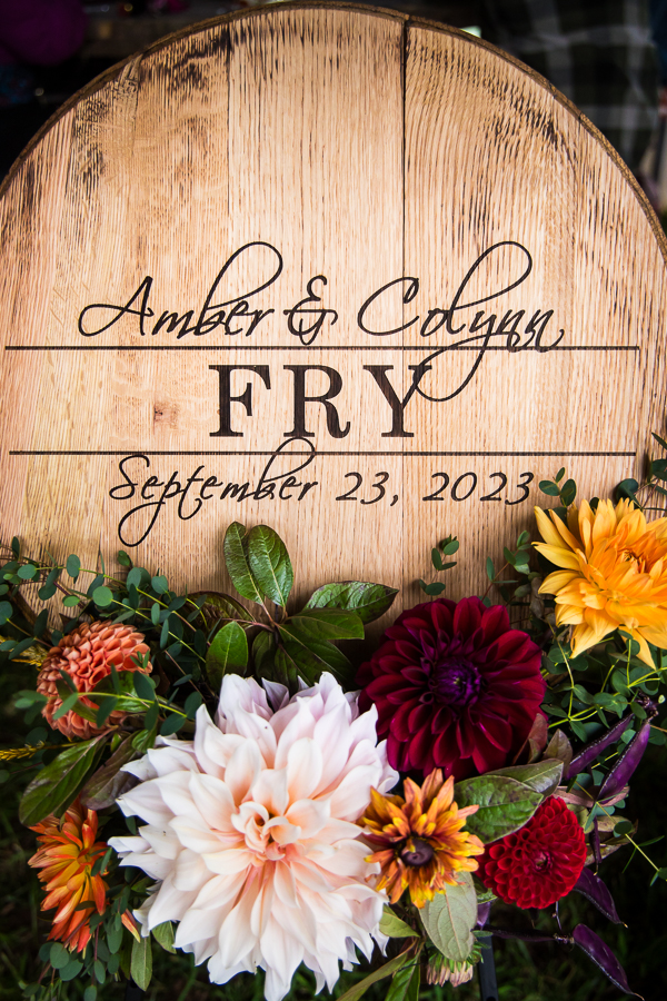 unique wedding decor inspo for a country wedding including vibrant fall florals and a sign featuring the couples name and date behind the wedding floral 