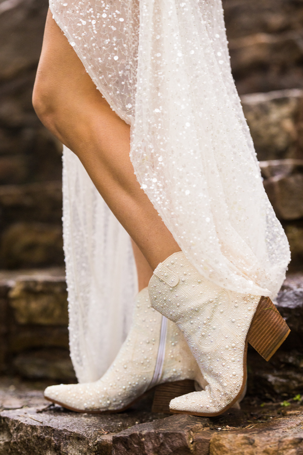pa country wedding photographer, lisa rhinehart, captures the pearl details on both the bride's white boots and reception dress during this country inspired wedding