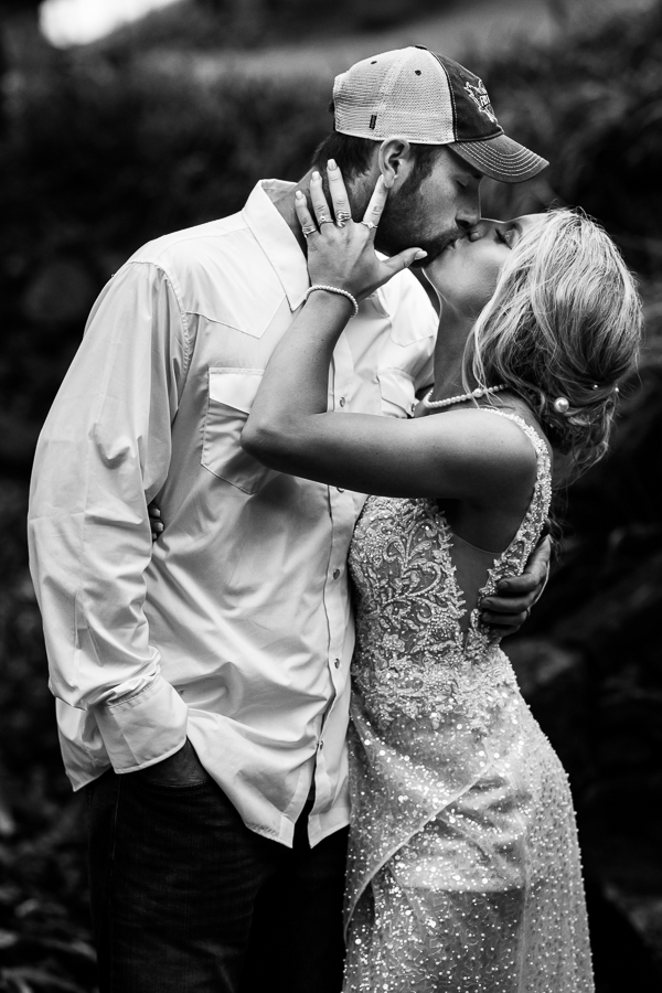 black and white image of the bride as groom as they share a kiss out in the field surrounded by the mountains during this outdoor country-inspired wedding reception captured by wild country wedding photographer, lisa rhinehart