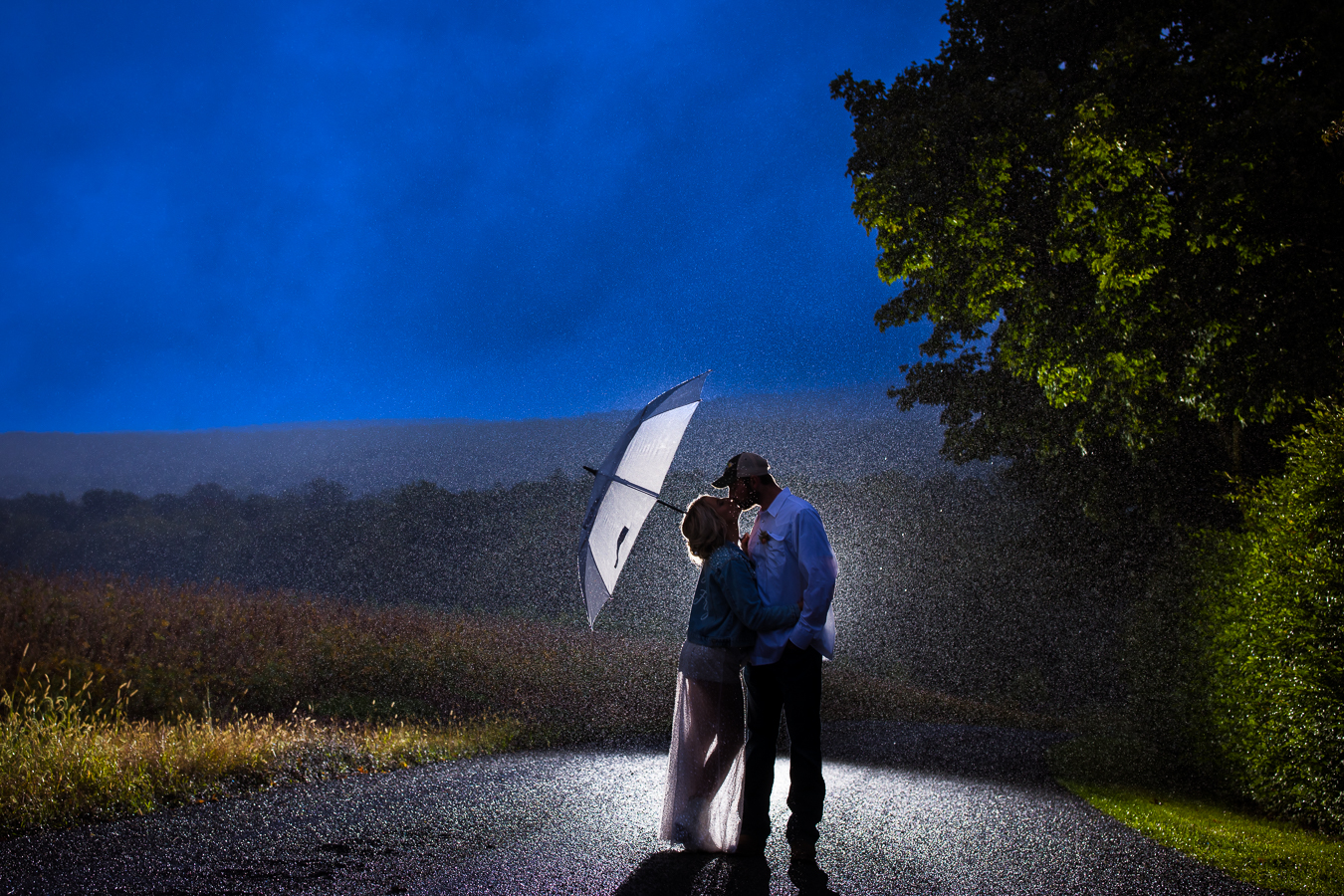 creative pa country wedding photographer, lisa rhinehart, captures this romantic night shot of the bride and groom as they stand on the road sharing a kiss in the middle of a downpour during their country inspired wedding