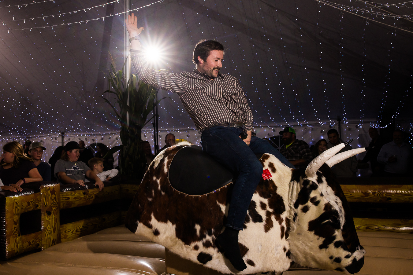 pa country wedding photographer, lisa rhinehart, captures this unique, fun reception moment of guests riding on the mechanical bull during this country wedding reception 
