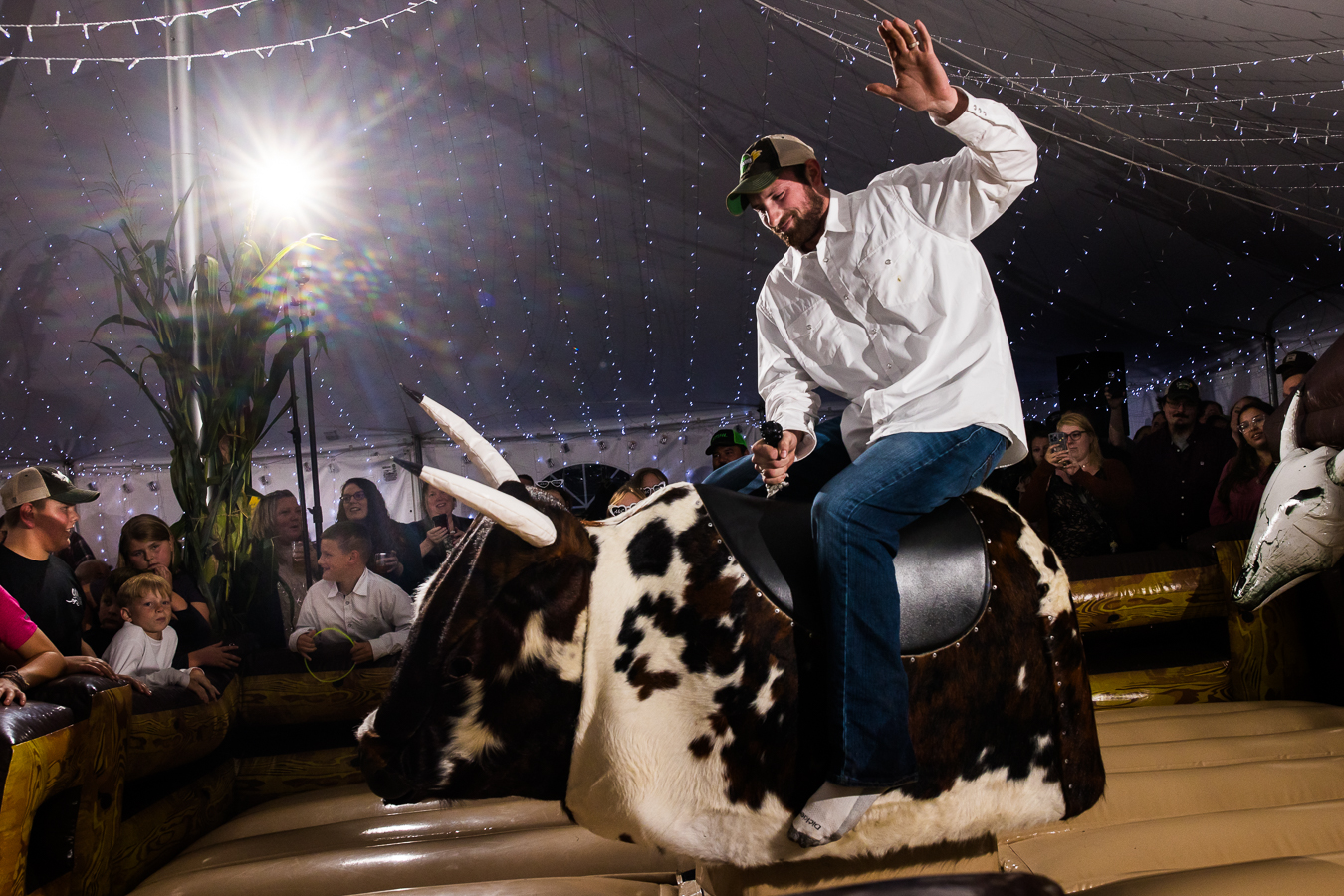 fun, candid image of the groom during this wild country wedding reception as he rides the mechanical bull at their country inspired wedding reception in halifax pa 