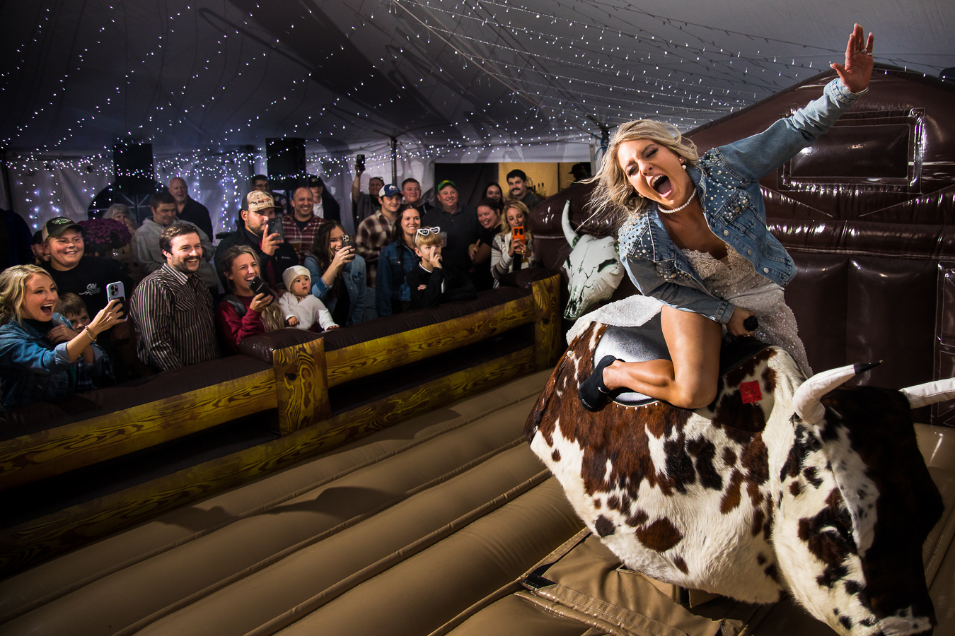 best pa country wedding photographer, lisa rhinehart, captures this candid, fun, unique and creative image of the bride and she is riding the mechanical bull during her wild country wedding reception in halifax pa 