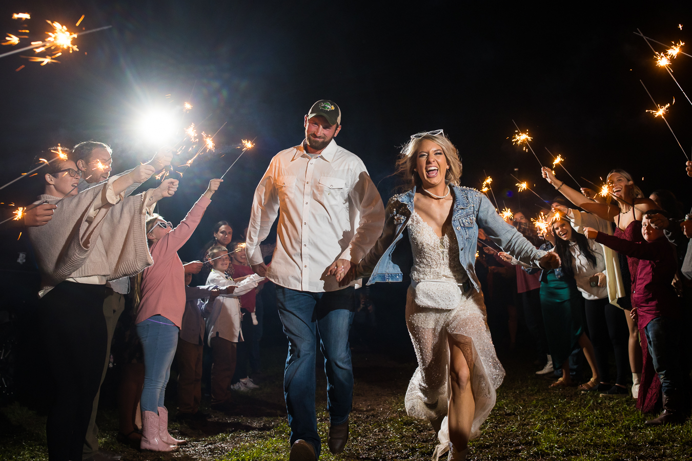 wild country wedding photographer, lisa rhinehart, captures this fun image of the bride and groom as they run through the middle of their guests holding sparklers during this country wedding sparkler send off in halifax pa 