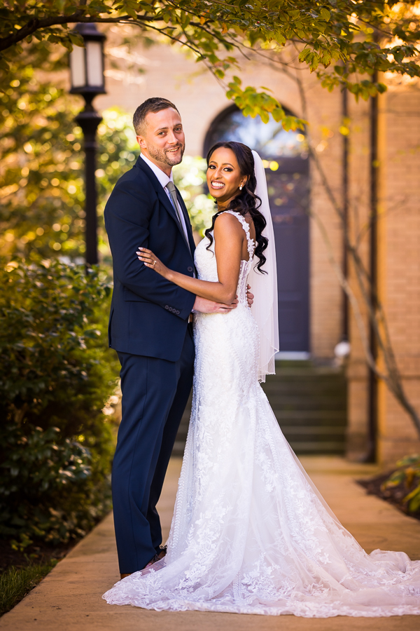 st francis hall wedding photographer, Lisa Rhinehart, captures this traditional portrait of the bride and groom as they wrap their arms around each other and smile at the camera before their Ethiopian infused wedding ceremony 