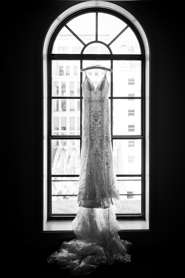 st regis hotel photographer, Lisa Rhinehart, captures this black and white image of the wedding gown handing from the window showing off the details on the dress 