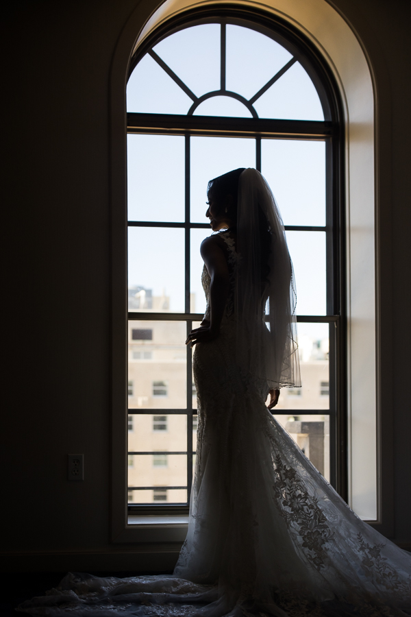 st regis hotel photographer, Lisa Rhinehart, captures this traditional bridal portrait silhouette of the bride looking out the window of st regis hotel before her st francis hall wedding ceremony 