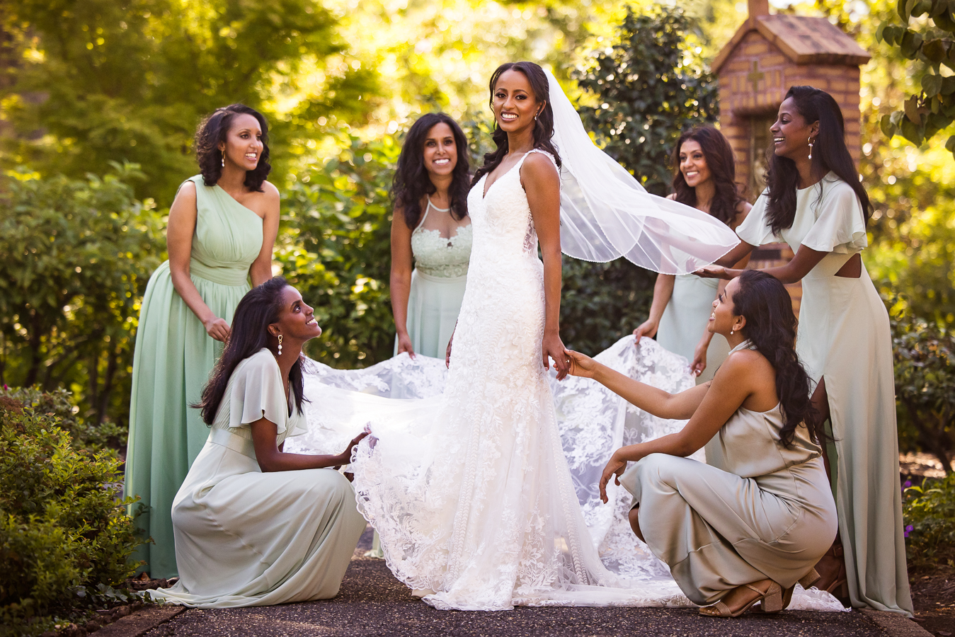 st Francis hall wedding photographer, Lisa Rhinehart, captures this stunning image of this Ethiopian bride with her bridesmaids as they all hold a part of the wedding gown as their dressed in their various shades of sage green for this multicultural wedding in dc