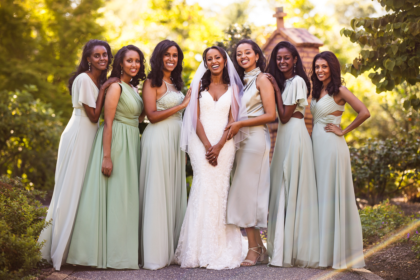 wedding photographer, Lisa Rhinehart, captures this traditional bridal party shot of the bride and her bridesmaids standing in a line smiling and laughing at the camera together outside of st francis hall 