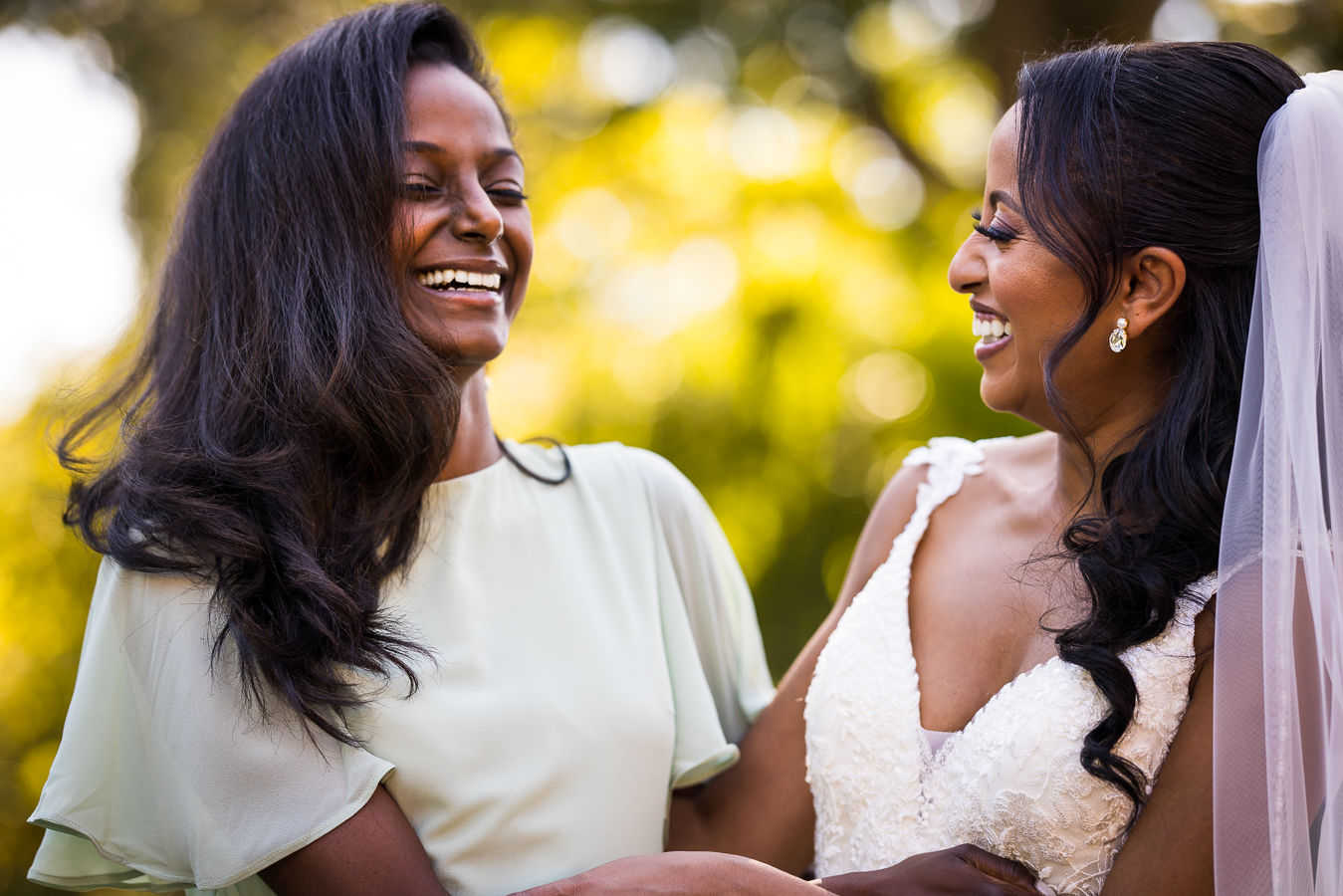 candid dc wedding photographer, Lisa Rhinehart, captures this candid moment between the bride and her bridesmaid as they laugh together outside of st francis hall 