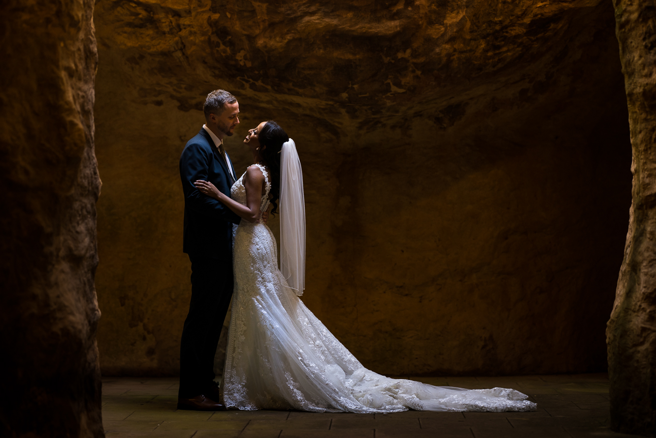 dc wedding photographer, Lisa Rhinehart, captures this image of the bride and groom hugging one another inside of a cave at st francis hall in Washington, dc during their Multicultural DC Wedding ceremony 