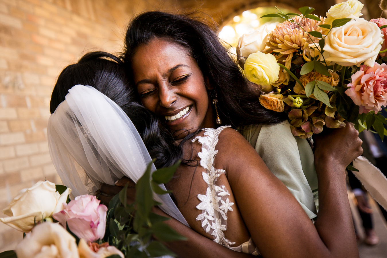 vibrant, colorful image of the bride as she hugs her bridesmaid after this Multicultural DC Wedding ceremony at st francis hall in Washington DC 