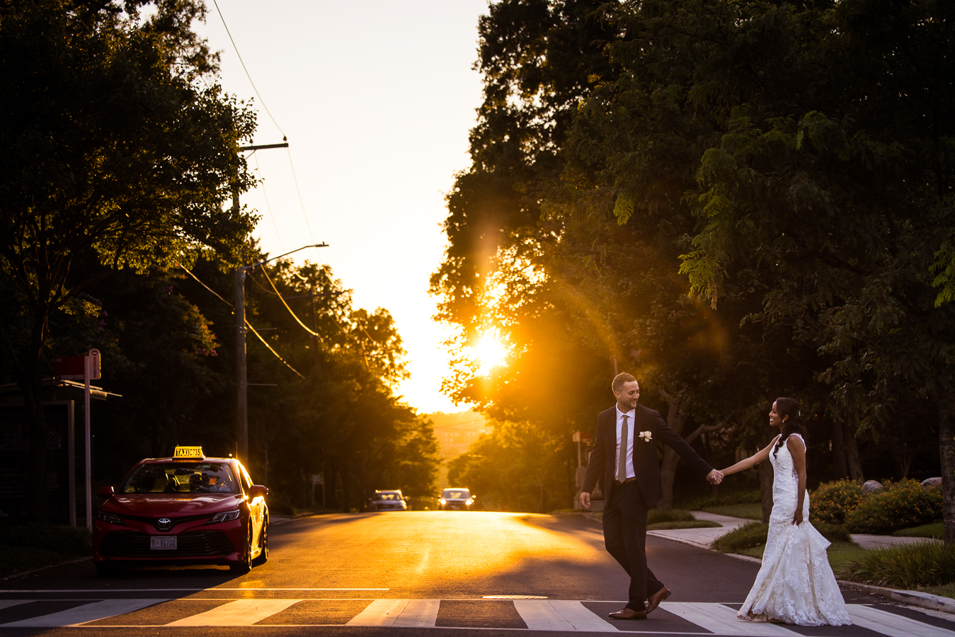golden hour image of the groom and his Ethiopian bride as they walk hand and hand across the crosswalk in downtown dc together as the sun sets behind them captured by dc wedding photographer, Lisa Rhinehart