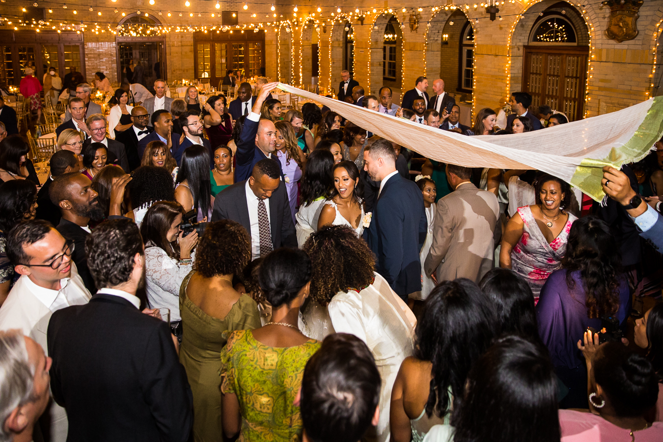 Multicultural DC Wedding photographer, lisa rhinehart, captures this image of the ethiopian bride and her groom underneath a blanket as they celebrate cultural wedding traditions during this st francis hall wedding reception in Washington dc 