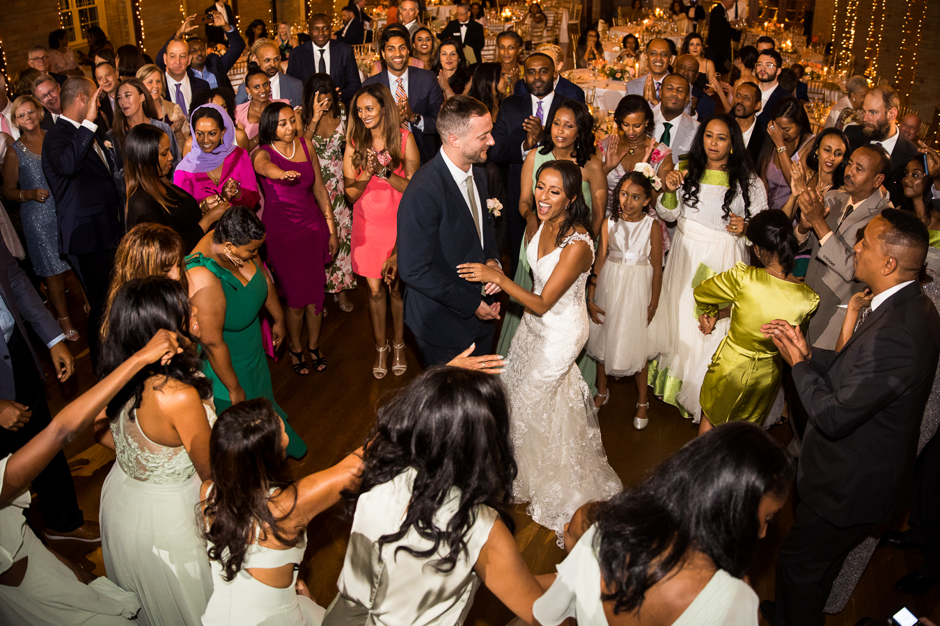 dc wedding photographer, lisa rhinehart, captures this image of the bride and groom in the middle of a dance circle as the ethiopian wedding traditions begin during this st francis hall wedding reception 