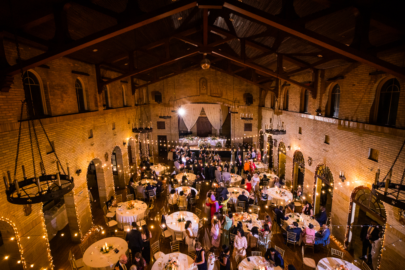 aerial image of st francis hall as wedding guests mingle with each other and dance together during this multicultural wedding reception 
