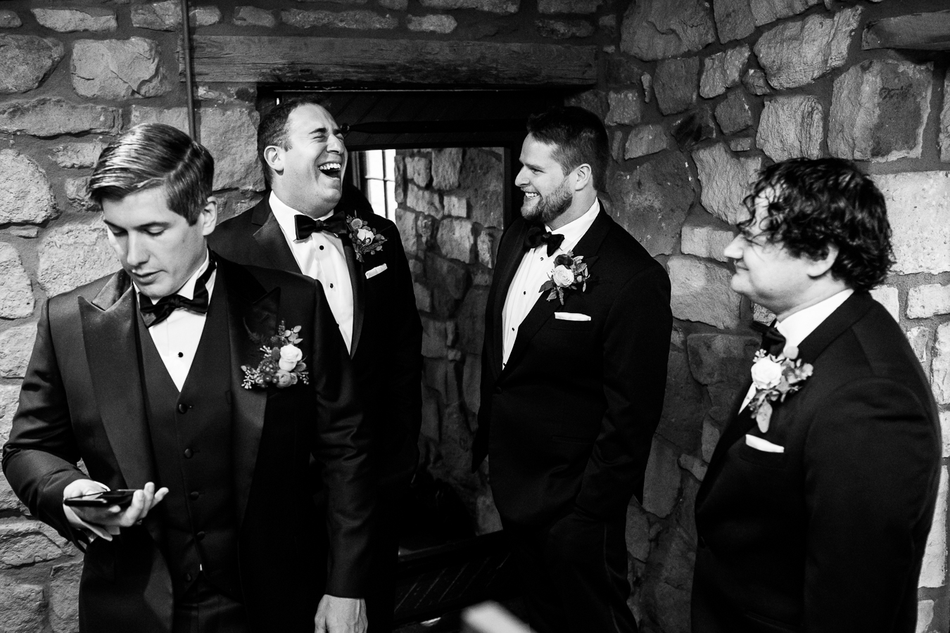 black and white candid moment of the groom and his groomsmen as they share a laugh together before this indoor rainy day wedding ceremony in Lancaster pa 