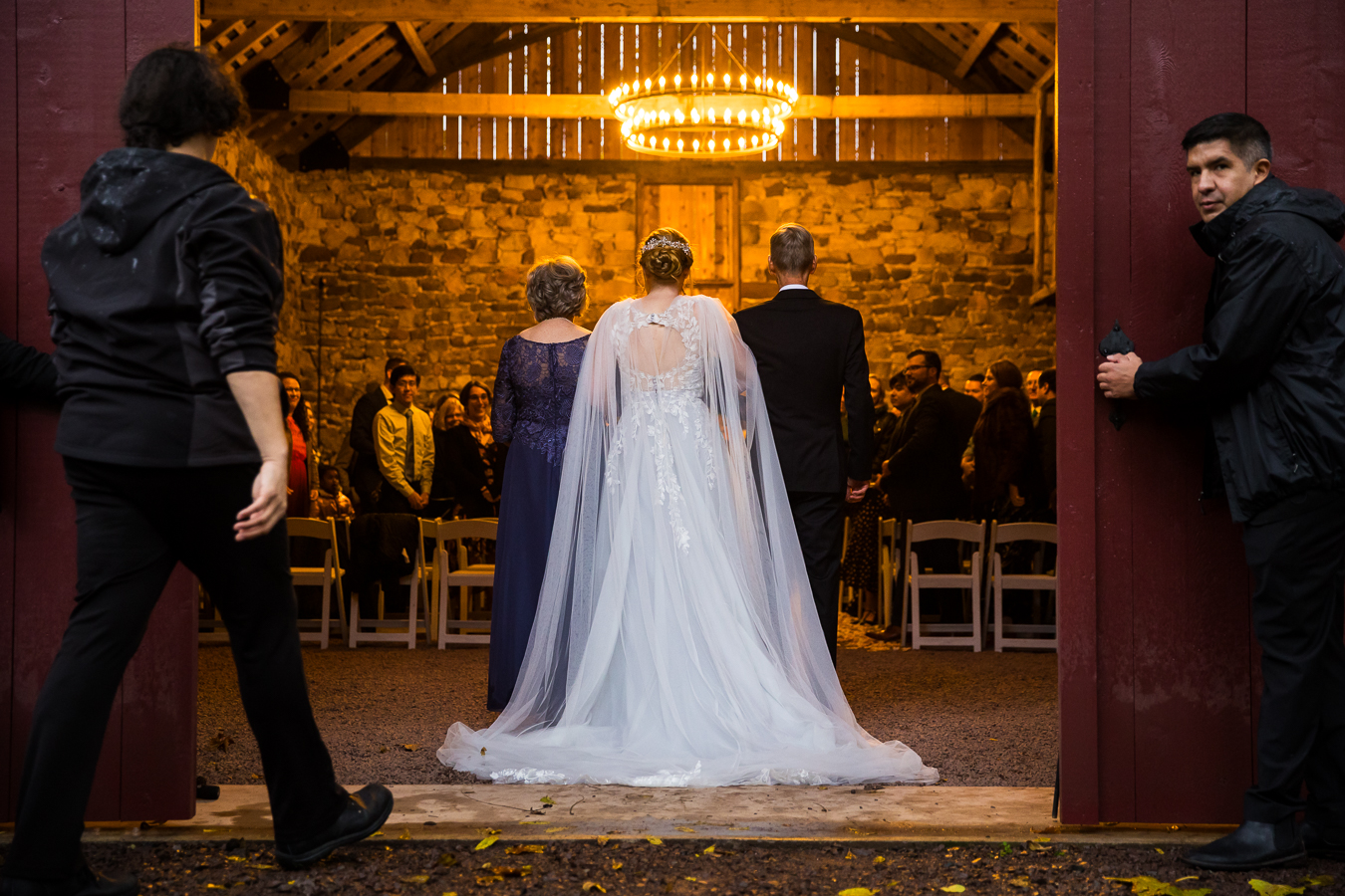 wedding photographer, rhinehart photography, captures this moment of the bride and her parents as they get ready to walk down the aisle during their wedding ceremony inside of this gorgeous stone barn in Lancaster pa 