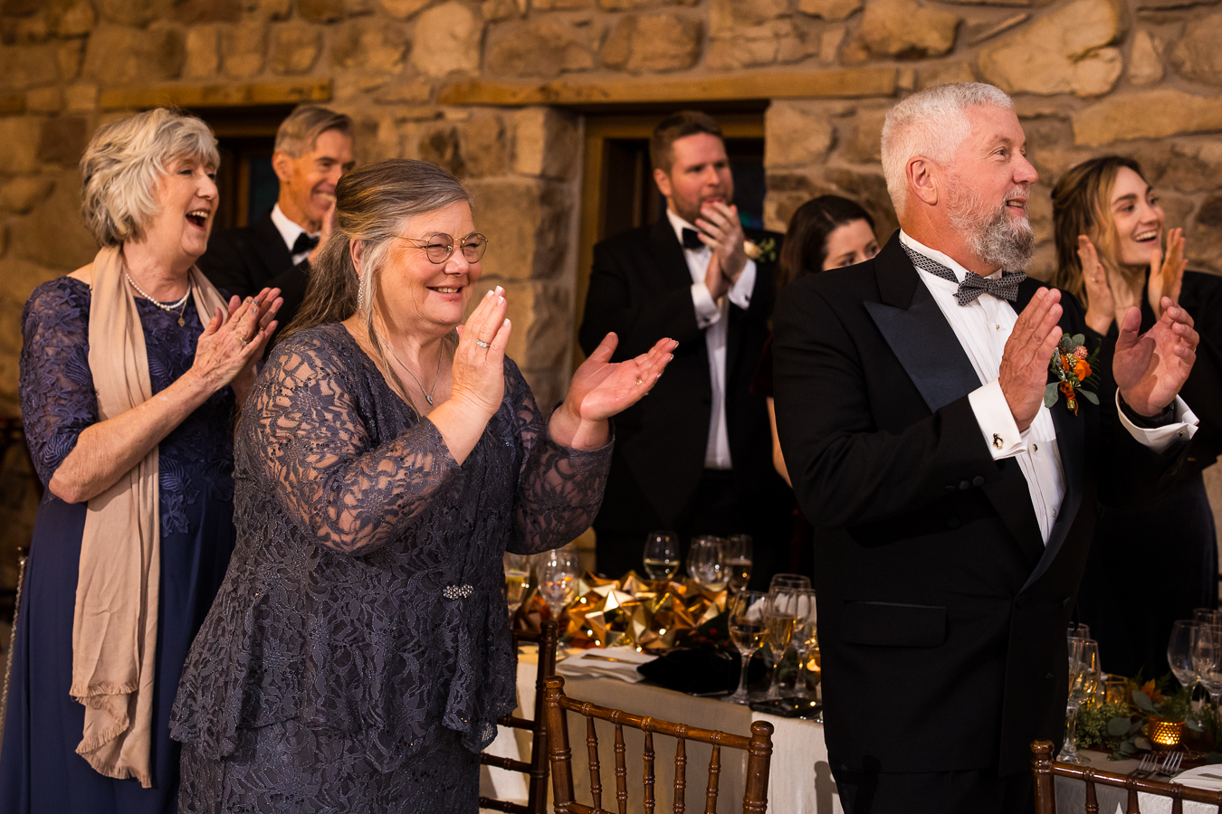 image of parents and guests as they smile and cheer for the couple as they share their first dance together during this indoor wedding reception 