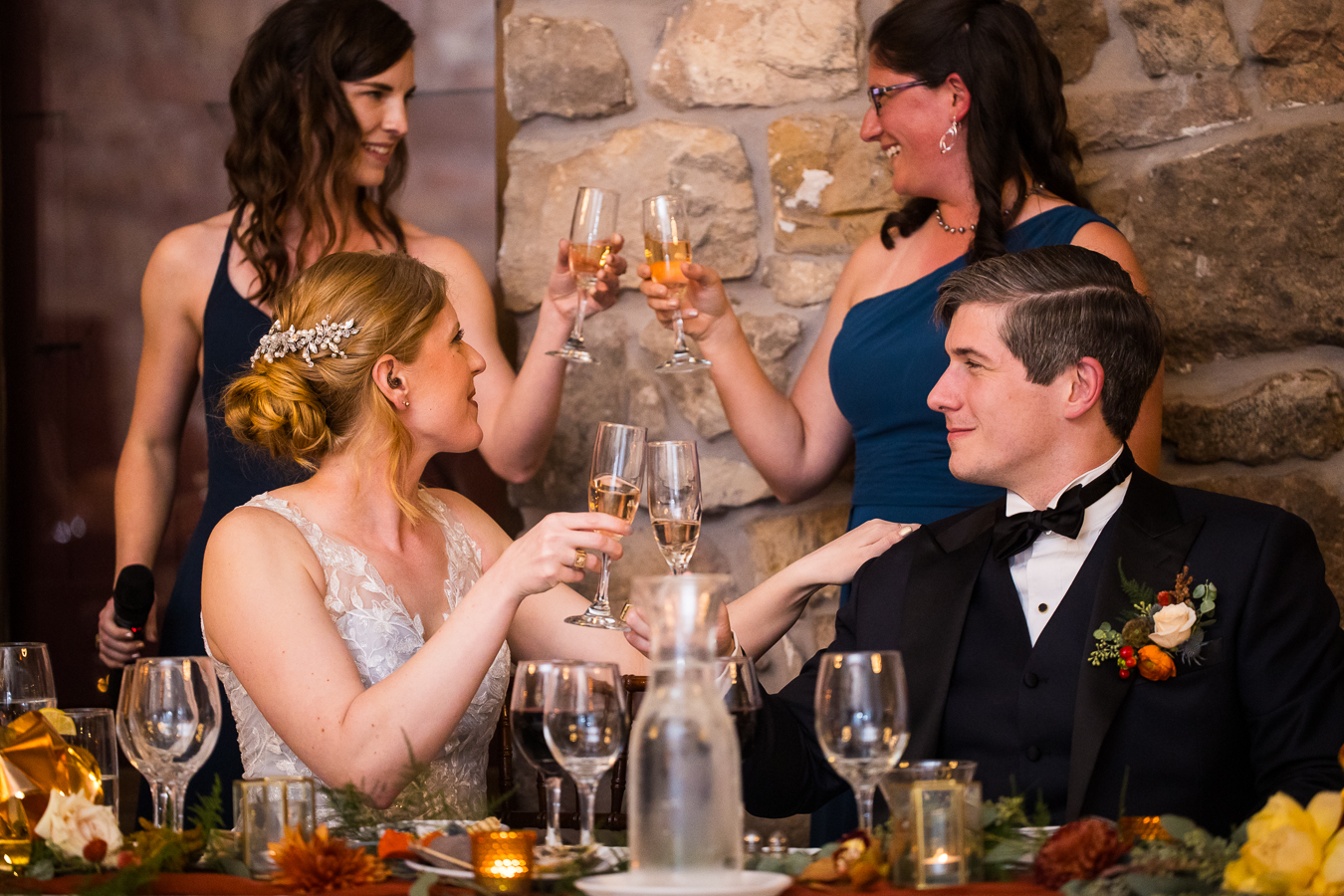 candid moment as the bride and groom share a toast as two bridesmaids share a toast behind them during their indoor wedding reception in lancast pa 