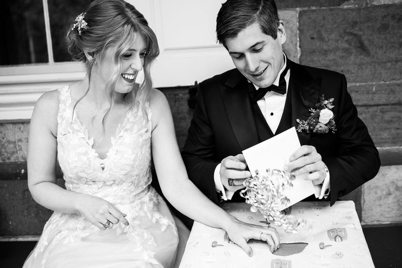 candid black and white moment of the bride and groom as they open gifts together during their wedding reception at the Elizabeth furnace in lititz pa 